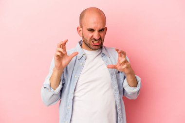 Genç beyaz kel adam pembe arka planda izole edilmiş gergin ellerle çığlık atıyor..