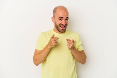 Beyaz arka planda izole edilmiş genç kel adam parmaklarıyla ön tarafı işaret ediyor..