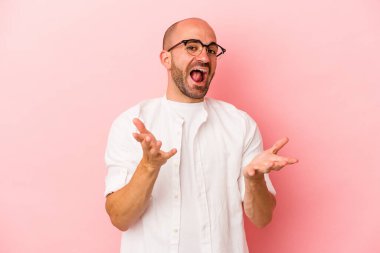 Pembe arka planda izole genç beyaz kel adam kameraya sarıldığı için kendinden emin hissediyor..