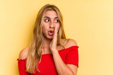 Sarı arka planda izole edilmiş beyaz, genç bir kadın gizli bir sıcak fren haberi veriyor ve yana bakıyor.