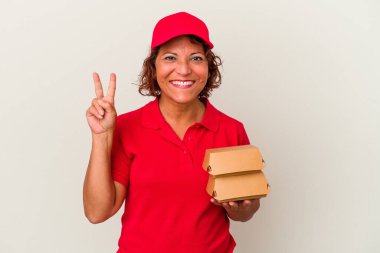 Burgerleri alan orta yaşlı bir kadın beyaz arka planda iki numarayı parmaklarıyla gösteriyor..