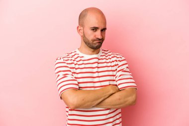 Genç, beyaz, kel bir adam pembe arka planda izole edilmiş şüpheli, belirsiz, seni muayene ediyor..