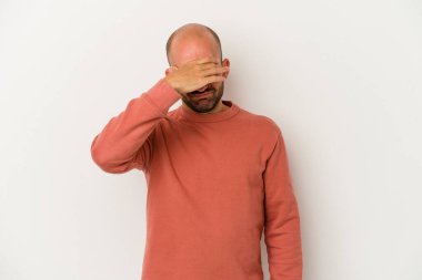 Beyaz arka planda soyutlanmış genç kel bir adam şakaklara dokunuyor ve başı ağrıyor..