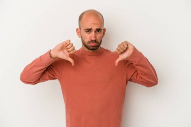 Genç kel bir adam beyaz arka planda izole edilmiş, hoşlanmadığı bir hareket sergiliyor, baş parmakları aşağıda. Anlaşmazlık konsepti.