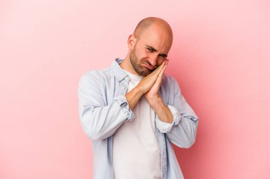 Pembe arka planda soyutlanmış beyaz kel bir adam esniyor. Ağzı eliyle kapatan yorgun bir hareket sergiliyor..