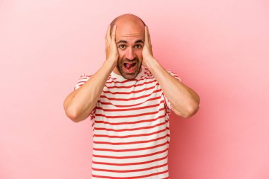 Genç, beyaz, kel bir adam pembe arka planda izole edilmiş bağırıyor, çok heyecanlı, tutkulu, bir şeyden memnun..