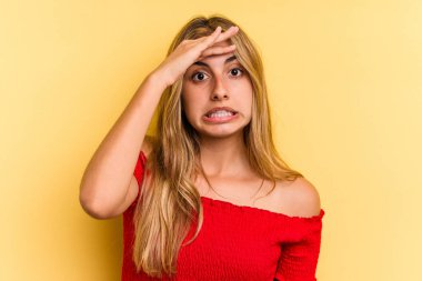 Sarı arka planda izole edilmiş genç beyaz kadın yüksek sesle bağırıyor, gözleri açık ve elleri gergin tutuyor..