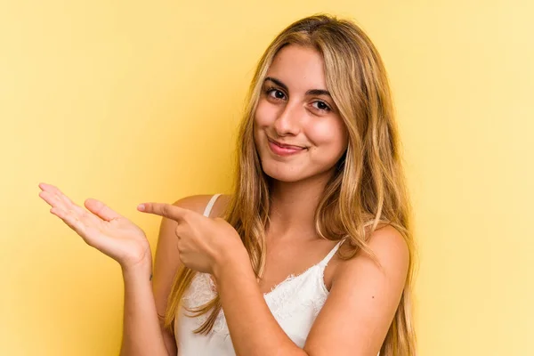 Joven Mujer Rubia Caucásica Aislada Sobre Fondo Amarillo Excitada Sosteniendo —  Fotos de Stock