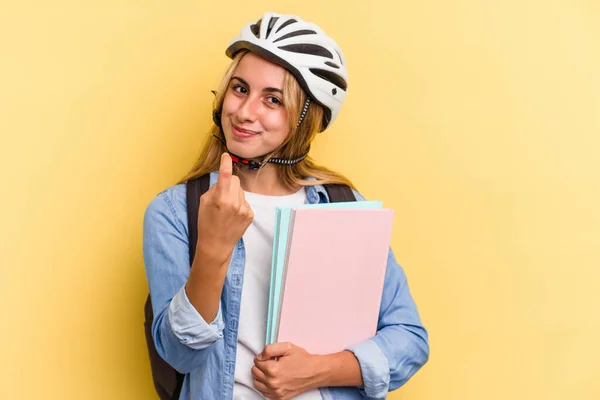 若いですCaucasian学生女性身に着けていますAバイクヘルメット隔離上の黄色背景Pointingとしてあなたに指で近くに来る — ストック写真