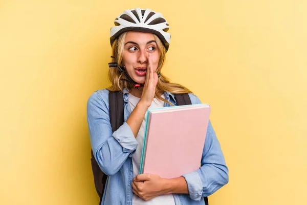若いです白人学生女性身に着けています自転車ヘルメット黄色の背景に隔離されていますと言っています秘密のホットブレーキニュースと脇を見て — ストック写真