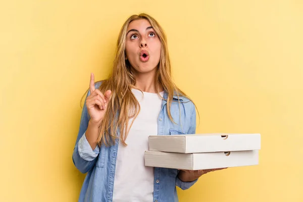 Jonge Kaukasische Blonde Vrouw Houden Pizza Geïsoleerd Gele Achtergrond Wijzend — Stockfoto