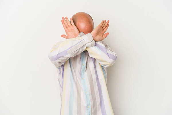 Молодой лысый человек изолирован на белом фоне держа две руки скрещенными, отрицание концепции.