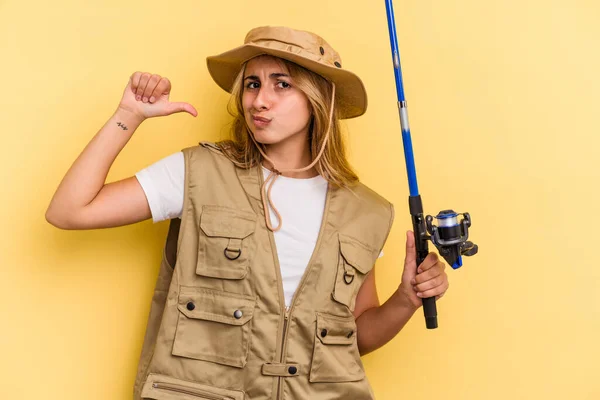 年轻的高加索金发女渔民拿着一根黄色背景的钓竿 感到自豪和自信 可以学习 — 图库照片