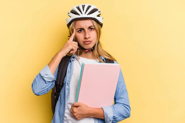 若い白人の学生の女性は 指で寺を指して黄色の背景に隔離された自転車のヘルメットを着て タスクに焦点を当て — ストック写真