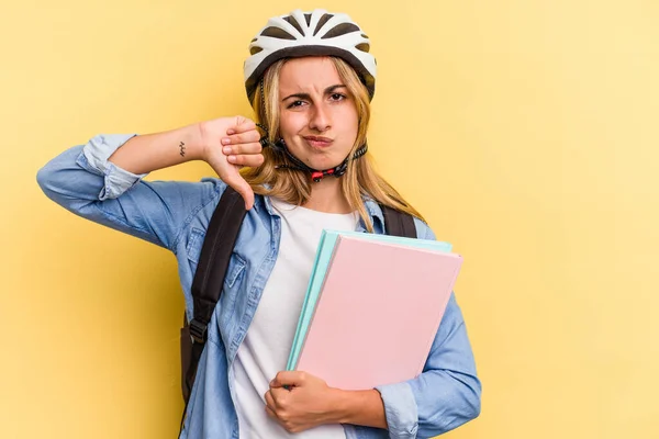 若い白人学生の女性は 黄色の背景には嫌いなジェスチャー 親指を示す隔離された自転車のヘルメットを着ている 意見の相違 — ストック写真