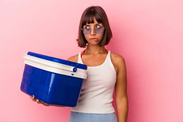 Young Mixed Race Woman Holding Cooler Isolated Pink Background Confused — Stock Photo, Image