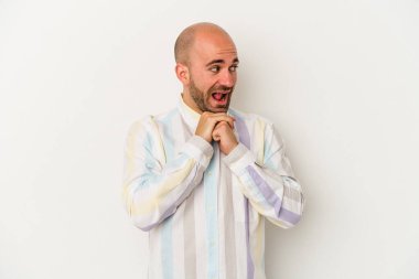 Beyaz arka planda izole edilmiş genç kel adam ellerini çenesinin altında tutuyor ve mutlu bir şekilde yan tarafa bakıyor..