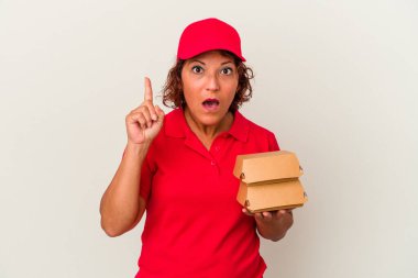 Beyaz arka planda soyutlanmış burgerleri alan orta yaşlı bir teslimatçı kadının bir fikri var, ilham verici bir kavram..