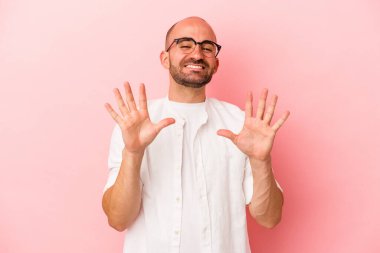 Pembe arka planda izole edilmiş beyaz saçlı genç adam on numarayı elleriyle gösteriyor..