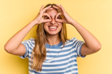 Sarışın, sarı arka planda izole edilmiş genç bir kadın. Gözlerinin üzerinde iyi bir işaret var.