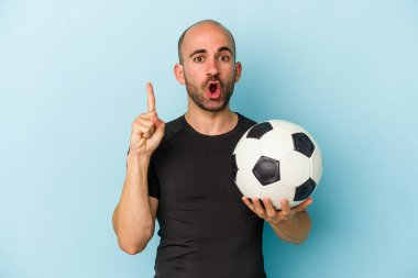 Genç iş adamı kel adam mavi arka planda tek başına futbol oynuyor. Harika bir fikri var, yaratıcılık kavramı..