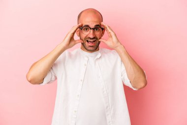 Genç beyaz kel adam pembe arka planda izole edilmiş. Hoş bir sürpriz bekliyor. Heyecanlı ve el kaldırıyor..