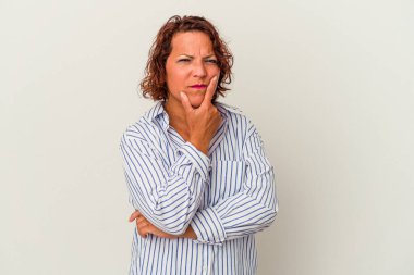 Beyaz arka planda izole edilmiş orta yaşlı Latin bir kadın şüpheli, belirsiz, seni muayene ediyor..