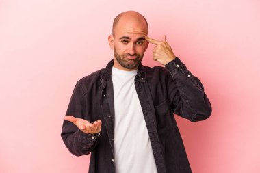 Beyaz saçlı genç adam pembe arka planda izole edilmiş ve elinde bir ürün var..