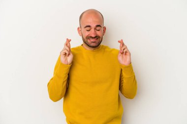 Genç kel adam beyaz arka planda izole edilmiş şans dilemek için şans diliyor.