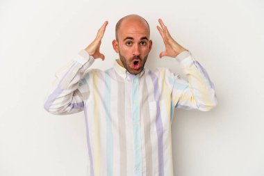 Genç kel adam beyaz arka planda zaferi ya da başarıyı kutlarken şaşırdı ve şok oldu..