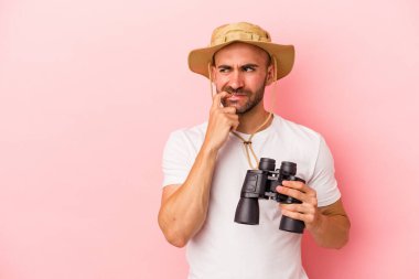 Pembe arka planda izole edilmiş dürbün tutan beyaz kel bir adam. Bir şeyin fotokopi alanına baktığını düşünüyor..