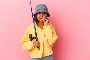 Genç melez kadın balık tutma pratiği yapıyor pembe arka planda izole edilmiş, parmakları dudaklarında sır saklıyor..