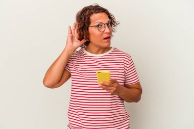 Beyaz arka planda izole edilmiş orta yaşlı Latin bir kadın bir dedikoduyu dinlemeye çalışıyor..