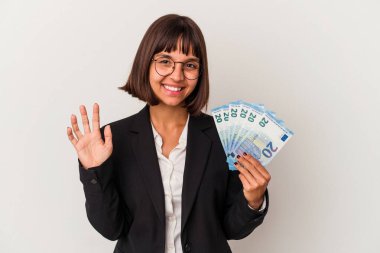 Genç melez iş kadını elinde banknotlarla beyaz arka planda izole edilmiş gülümseyen beş numarayı parmaklarıyla gösteriyor..