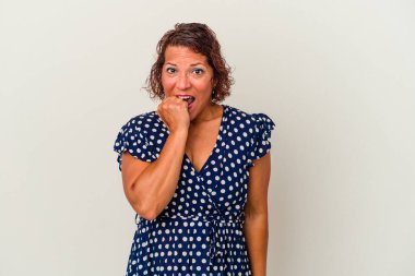 Beyaz arka planda izole edilmiş, tırnak yiyen, gergin ve endişeli orta yaşlı bir Latin kadın..