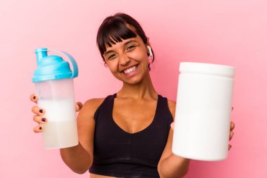 Genç melez kadın pembe arka planda izole edilmiş protein içeceği içiyor.