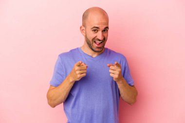 Pembe arka planda izole edilmiş beyaz, kel bir adam parmaklarıyla ön tarafı işaret ediyor..