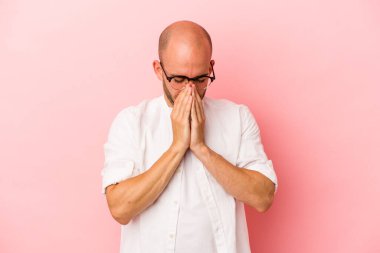 Kafkasyalı genç kel adam pembe arka planda izole edilmiş dua ediyor, bağlılık gösteriyor, dindar biri ilahi ilham arıyor..