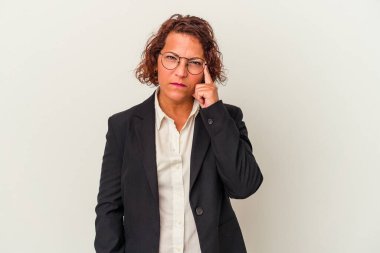 Orta yaşlı Latin iş kadını beyaz arka planda izole edilmiş. Şakağı işaret ediyor, düşünüyor, bir göreve odaklanıyor..