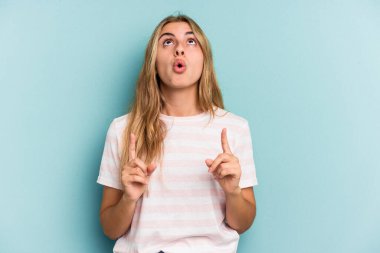 Mavi arka planda izole edilmiş, ağzı açık, üst tarafı gösteren beyaz, sarışın bir kadın..