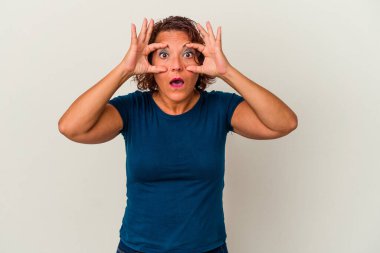 Beyaz arka planda izole edilmiş orta yaşlı Latin bir kadın bir başarı fırsatı bulmak için gözlerini açık tutuyor..