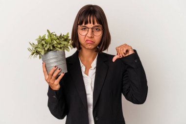 Genç melez bir iş kadını beyaz arka planda izole edilmiş bir bitki tutuyor. Sevimsiz bir hareket sergiliyor. Anlaşmazlık konsepti.