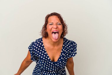 Beyaz arka planda izole edilmiş orta yaşlı Latin bir kadın komik ve dost canlısı bir dil uzatıyor..