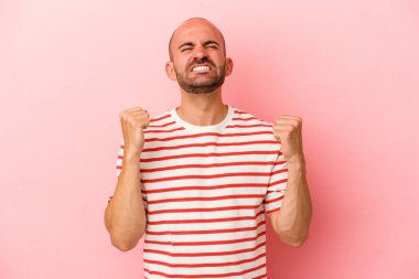 Pembe arka planda soyutlanmış beyaz kel bir adam zaferi, tutkuyu ve coşkuyu kutluyor, mutlu bir ifade..