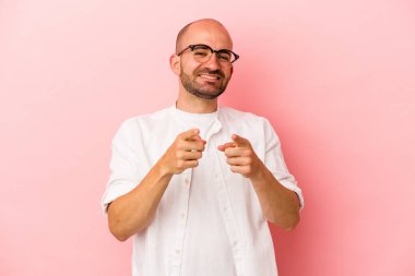 Pembe arka planda izole edilmiş beyaz, kel bir adam parmaklarıyla ön tarafı işaret ediyor..