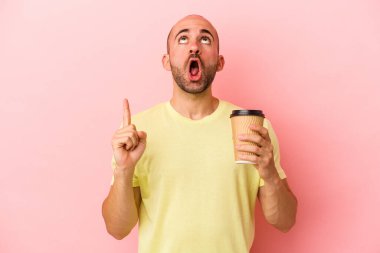 Kafkasyalı genç kel bir adam pembe arka planda izole edilmiş, ağzı açık bir kahve tutuyor..