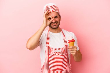 Dondurma yapan genç adam pembe arka planda izole edilmiş dondurma tutuyor..