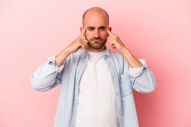 Pembe arka planda soyutlanmış beyaz kel bir adam bir göreve odaklanmış, parmaklarını işaret ediyor..