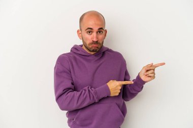 Beyaz arka planda izole edilmiş genç kel adam işaret parmağıyla bir kopyalama alanını işaret ederek şok oldu..