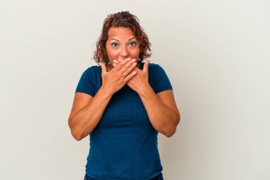 Beyaz arka planda izole edilmiş orta yaşlı Latin bir kadın elleriyle ağzını kapatırken şok oldu..